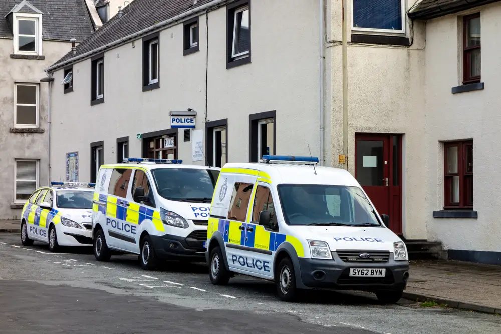 Marked police vans and a patrol car parked outside a station, essential police officer equipment for operational duties.