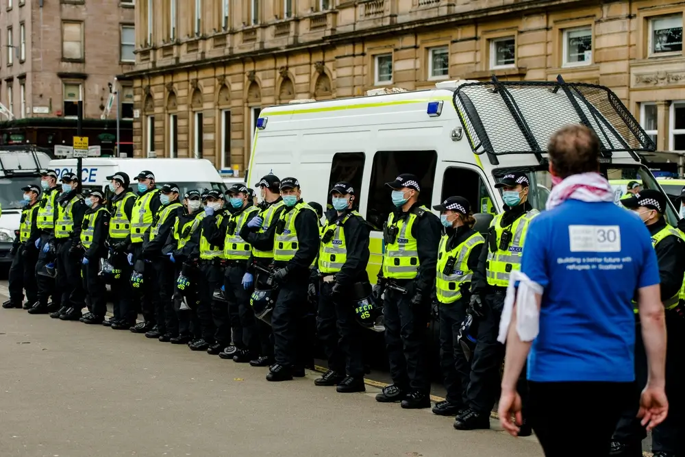 Police recruits in high-visibility uniforms and masks standing in formation at a police recruits training academy.