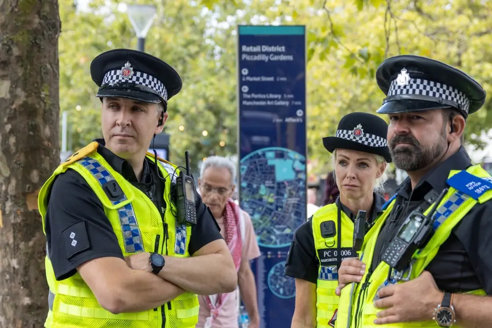 Officers wearing high visibility vests and essential police equipment like radios while on duty in a public city area.