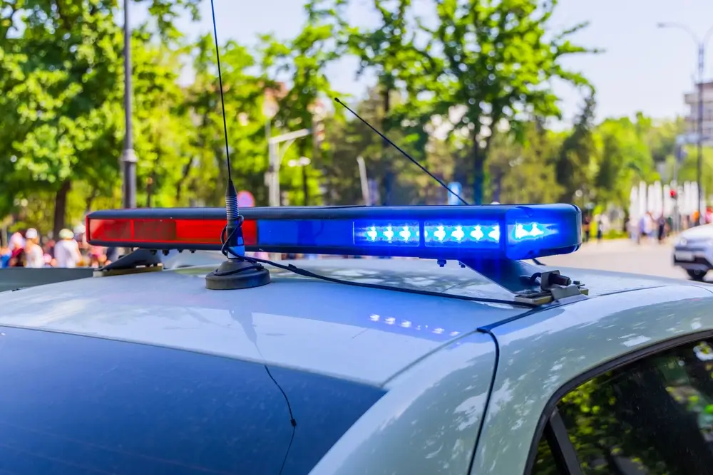 Flashing blue emergency lights on the roof of a police vehicle parked on a sunny city street.